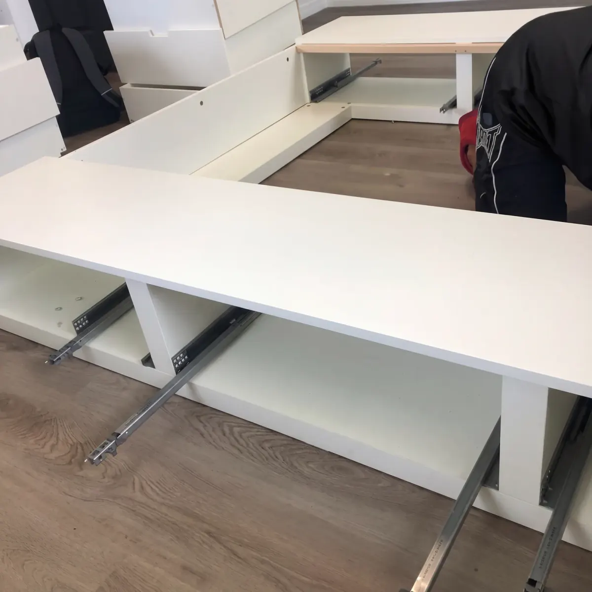 A mover working beside white storage-bed sections with exposed drawer runners