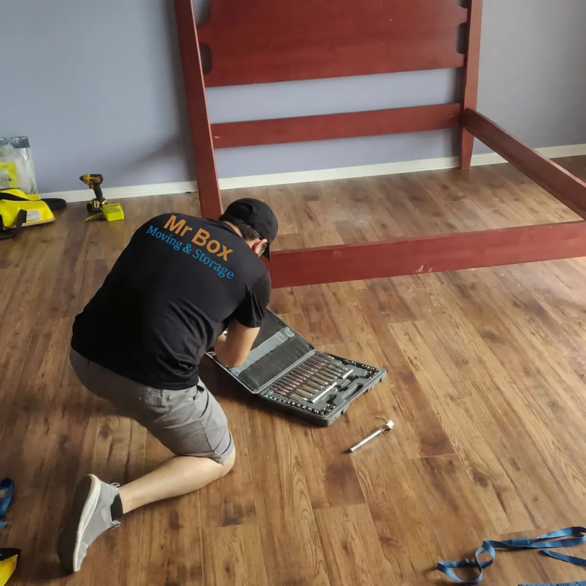 A Mr. Box mover selecting tools beside a wooden bed frame