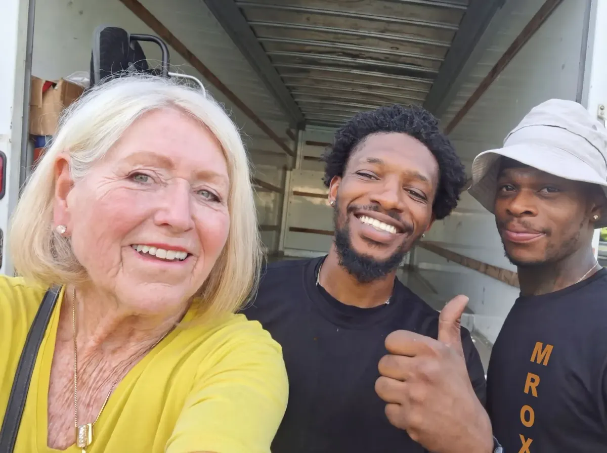 A customer taking a selfie with two Mr. Box movers beside a truck