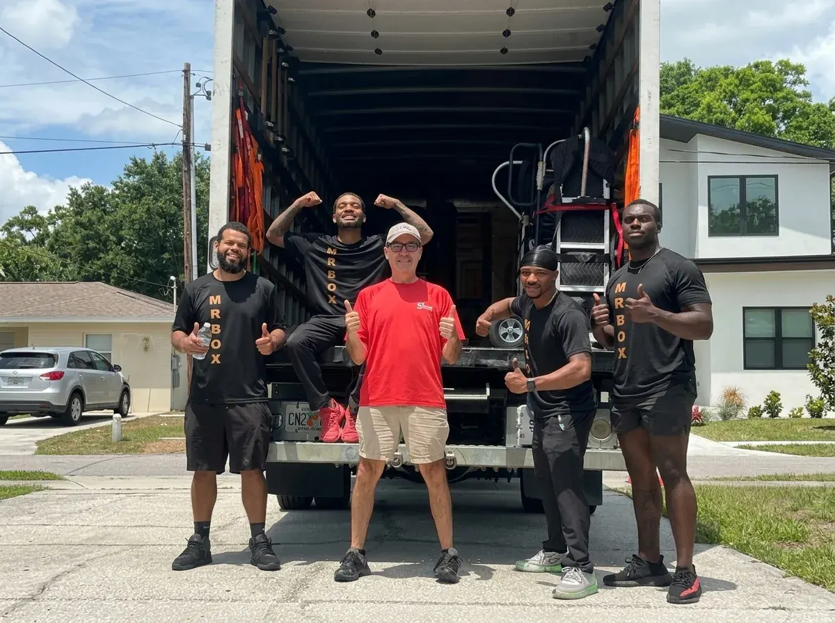 A customer in a red shirt posing with four movers at the back of a truck
