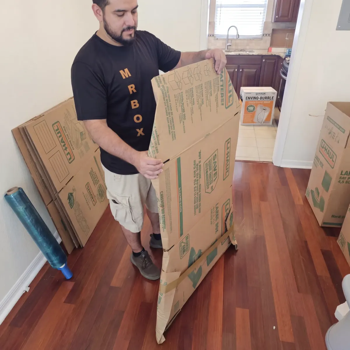 A Mr. Box mover shaping cardboard packing material inside a home